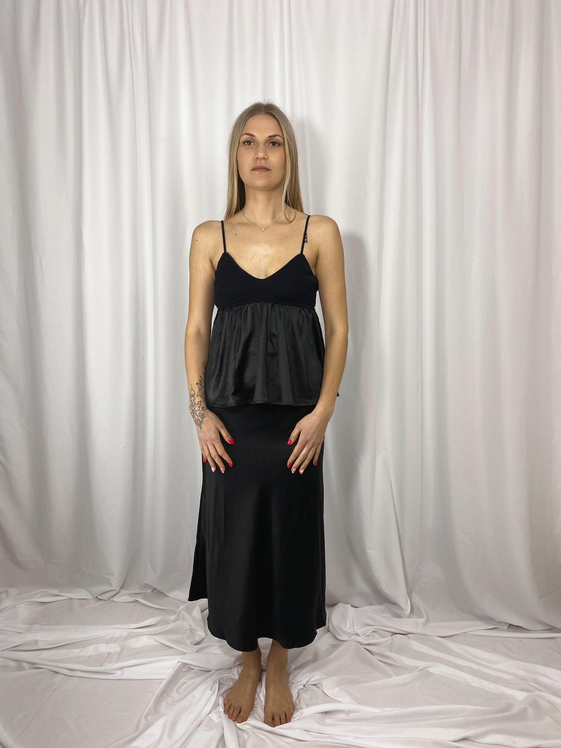 Caraco noir Lola en satin et maille porté avec jupe satinée
