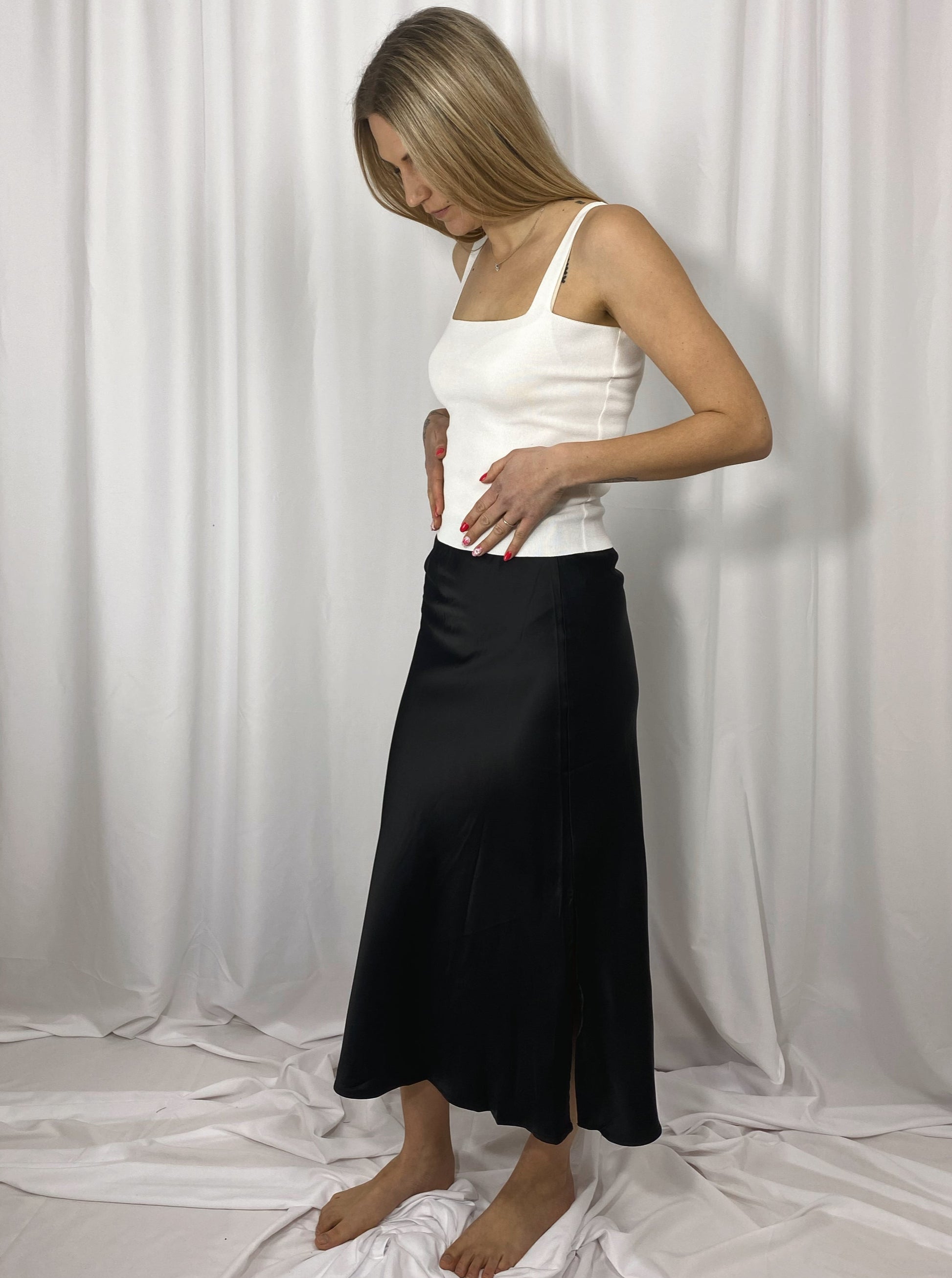 Jupe noire en satin fluide fendue sur le côté portée avec un top blanc - Maison Clémentine

